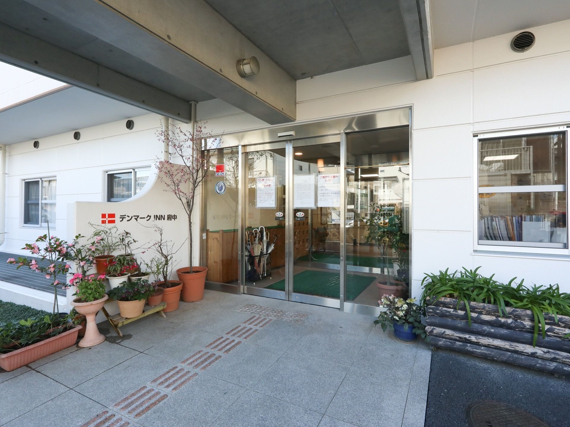 玄関ドアは、ガラス張りで両開きの自動ドアである。中には玄関フードを備えている。ドアの両側には鉢植えの観葉植物が並べられている。