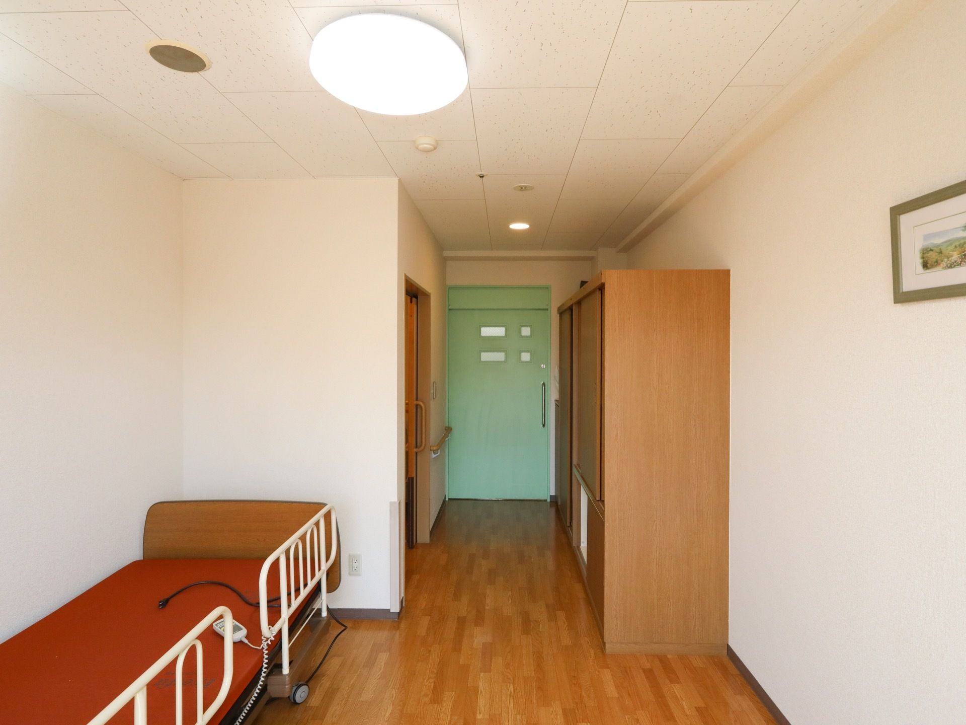 洋式ワンルームの居室で、入口近くにトイレと収納が備え付けられている。入口は小さな窓付きのスライドドアである。