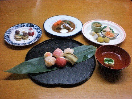 てまり寿司やビーフシチュー、前菜の盛り合わせ、澄まし汁、サンタのデザートなどがそれぞれきれいに器にも盛られている。