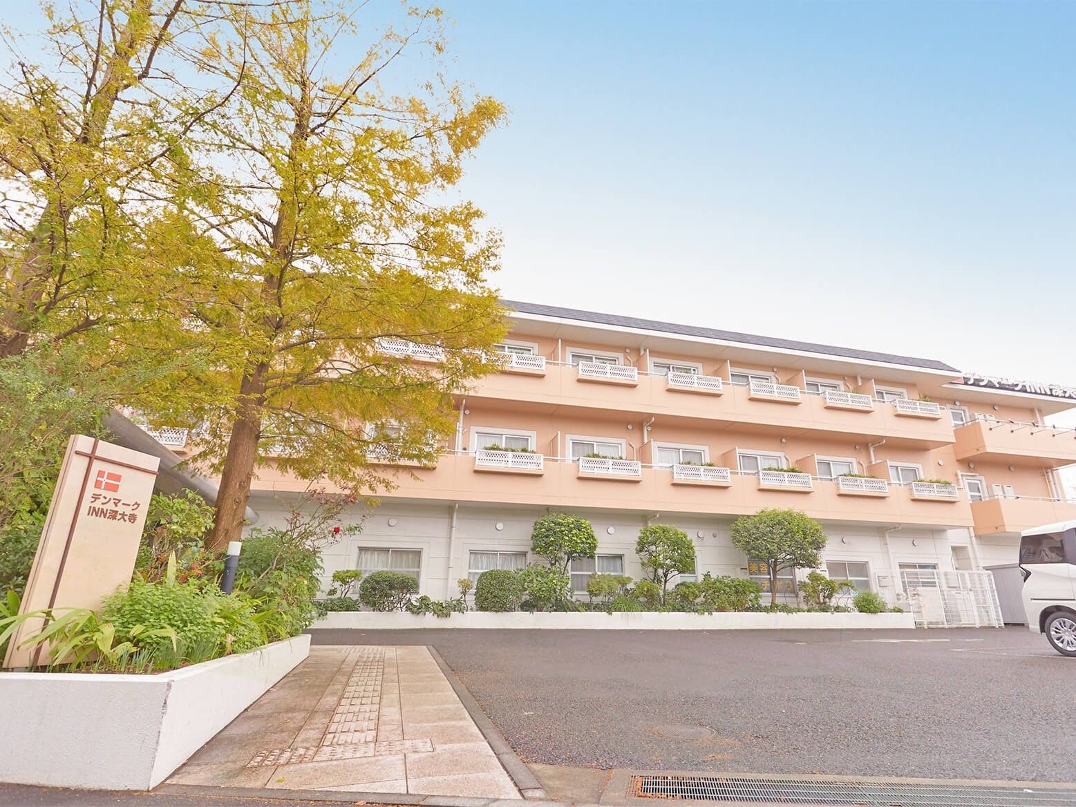 3階建ての建物は横に長く、敷地内には広い駐車場や木が植えられたスペースがある。