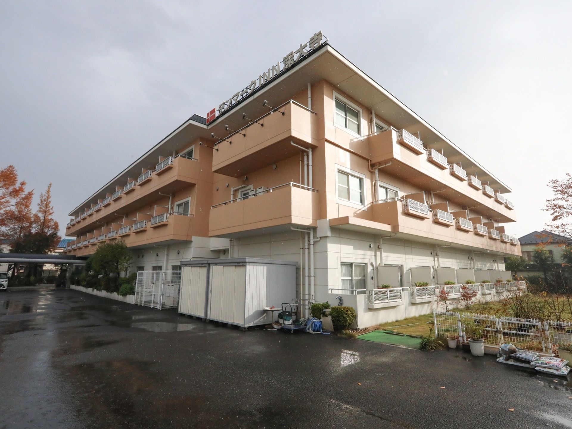 白とベージュを基調とした3階建ての住宅が建っている。敷地は舗装されており、建物の横には芝生の庭が広がっている。