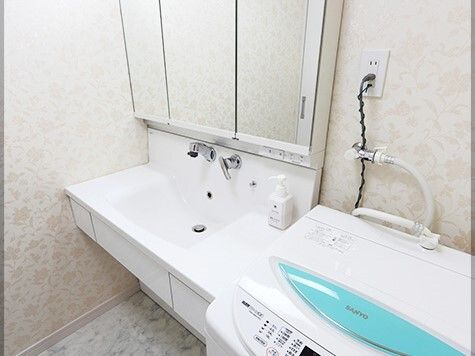 鏡裏収納が付いたワイドタイプの洗面所は車いす対応の造りで、横には洗濯機が置かれている。