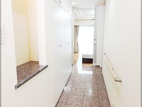 玄関を入って右の壁には手すりがあり、左側には壁面収納があり、飾り棚も設置されている。