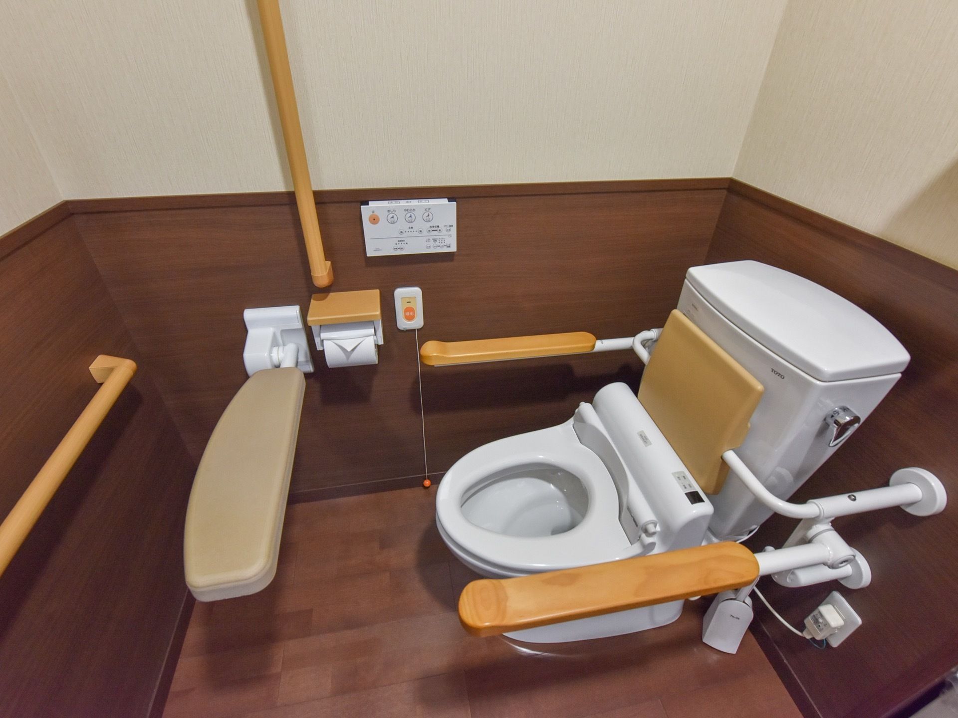床はフローリング。壁には備え付けの手すりがあり、便座の周囲には可動式の手すりも設置されている。ナースコールも用意されている。