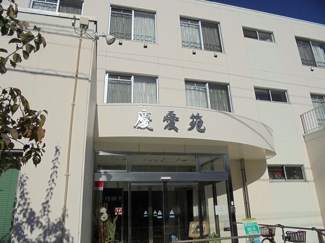 曲線デザインの玄関ポーチに大きく施設名を記した白色の建物