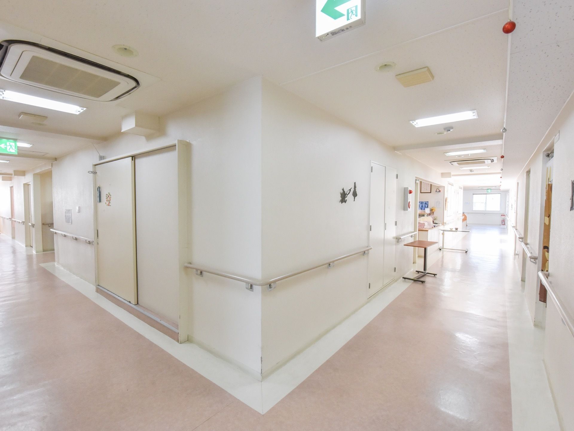 白い壁紙が明るく開放的な廊下がある。壁の両側には手すりが取り付けてある。床は２色使われて、歩行の目印となっている。