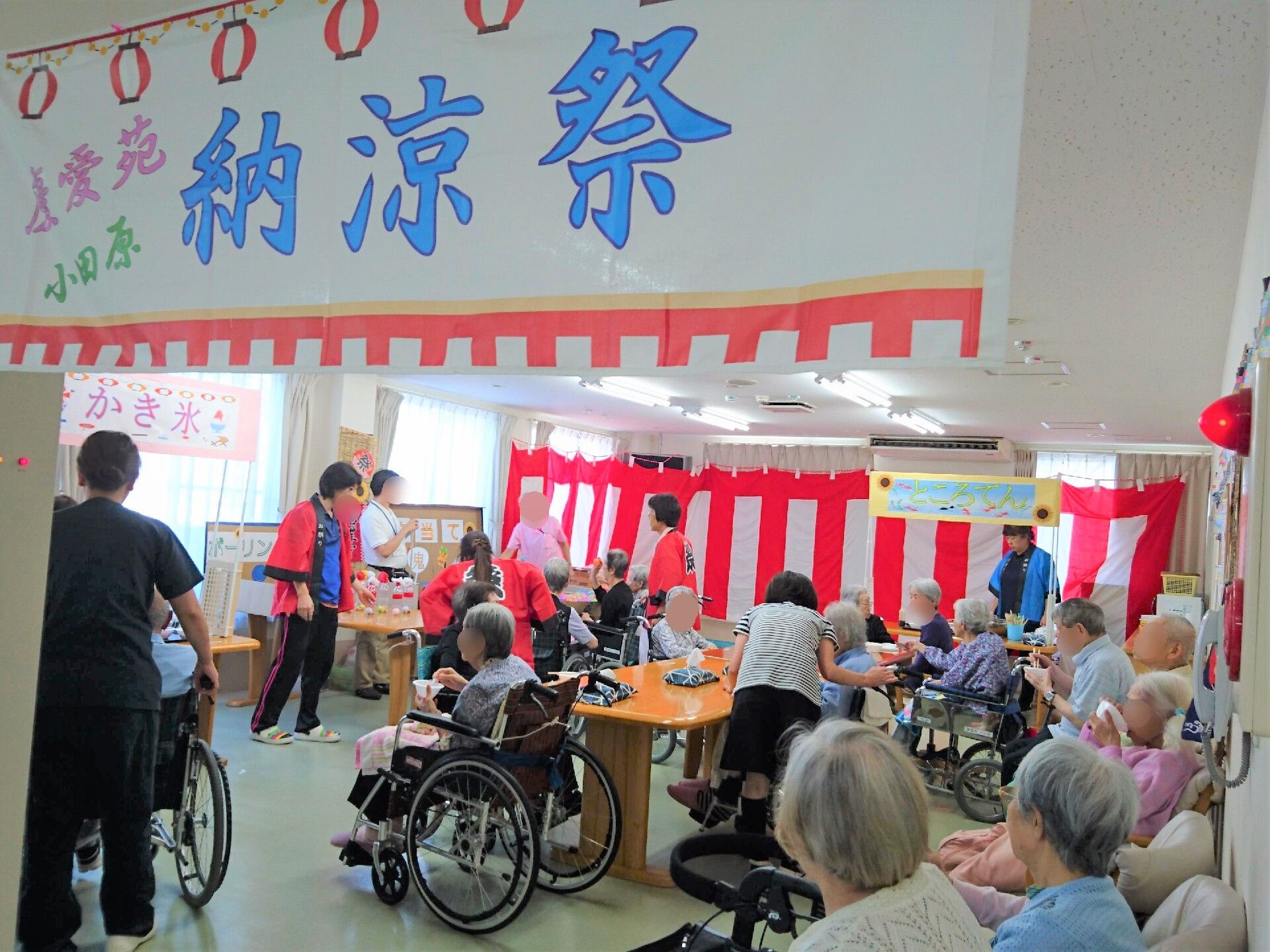 部屋を紅白幕や垂れ幕で飾り、お祭りを楽しむ大勢の入居者の皆様