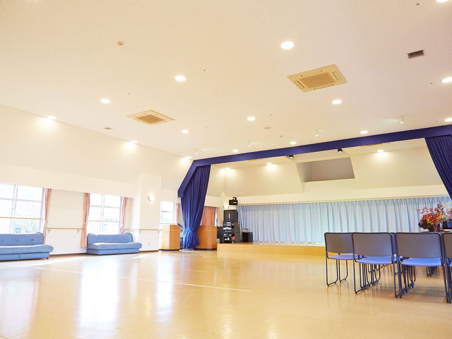 体育館のような広さの施設内のホール。開放的で広いスペースの隅にソファが置いてある様子