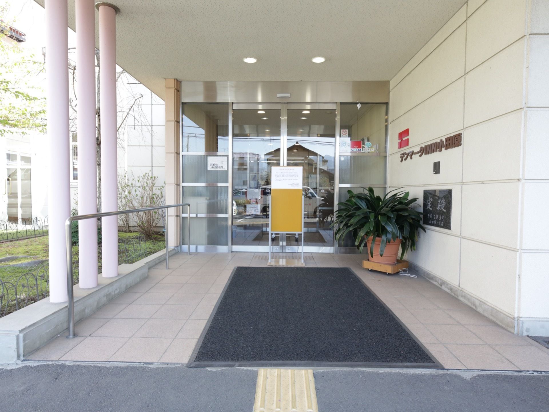 広いピロティの付いた玄関。入口は自動ドアになっており、端にはステンレスの手すりが備え付けられている。