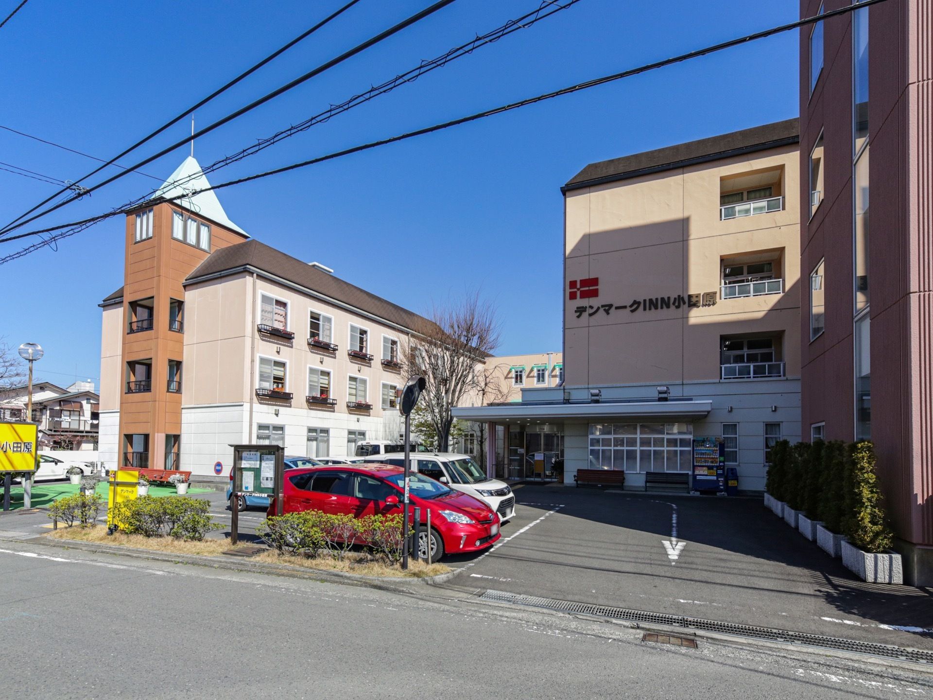 白やクリーム色など、やわらかい色を基調とした４階建ての施設が建っている。敷地は舗装され、駐車スペースになっている。