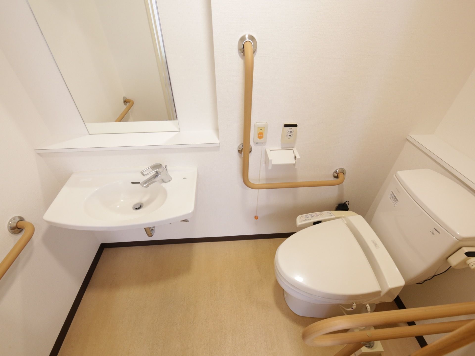 温水洗浄便座の付いたトイレがある。壁には手すりが備え付けられている他、ナースコールも設置されている。