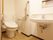 洗面台付きのトイレがある。床は木目調で、壁には手すりがある。手すりの近くにはナースコールが付いている。