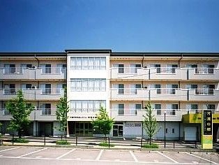 ホームの外観。4階建ての建物は横に長くパステルカラーで温かい雰囲気。駐車スペースも完備。