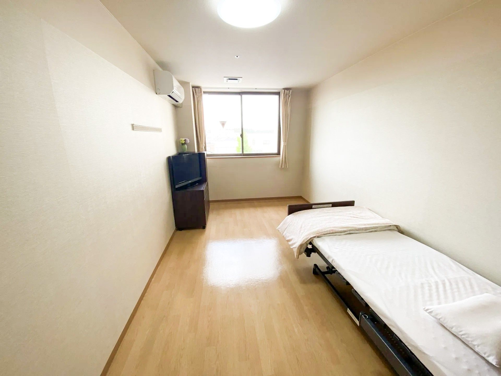 拍手をしながら楽しそうに何かを鑑賞している白髪の高齢女性とピンクのポロシャツを着た女性スタッフ。