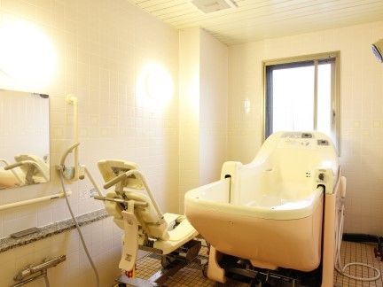 白い機械浴槽が置かれた広い浴室は洗い場がゆったりとしていて、シャワーや手すりも設置されている。
