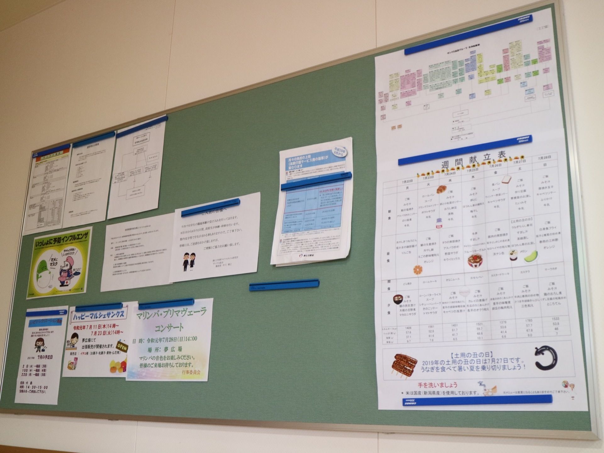 壁に、掲示板としてボードが設置されている。献立表や催し物、予防接種などのお知らせが貼り出されている。