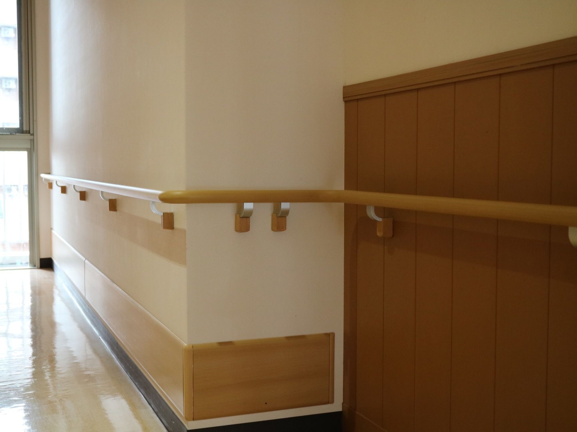 廊下は突き当たりが窓になっていて、日の光が室内に入り明るい雰囲気。安全のため、壁には手すりが設置されている。