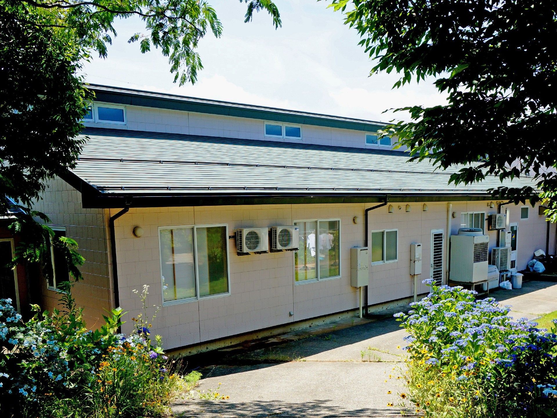 横に長い２階建ての建物の写真。介護用施設で個室が並んでいる建物であることが分かる