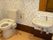 ふたの付いていない温水便座が設置されたトイレと洗面所がある。トイレの横には手すりも付いている。