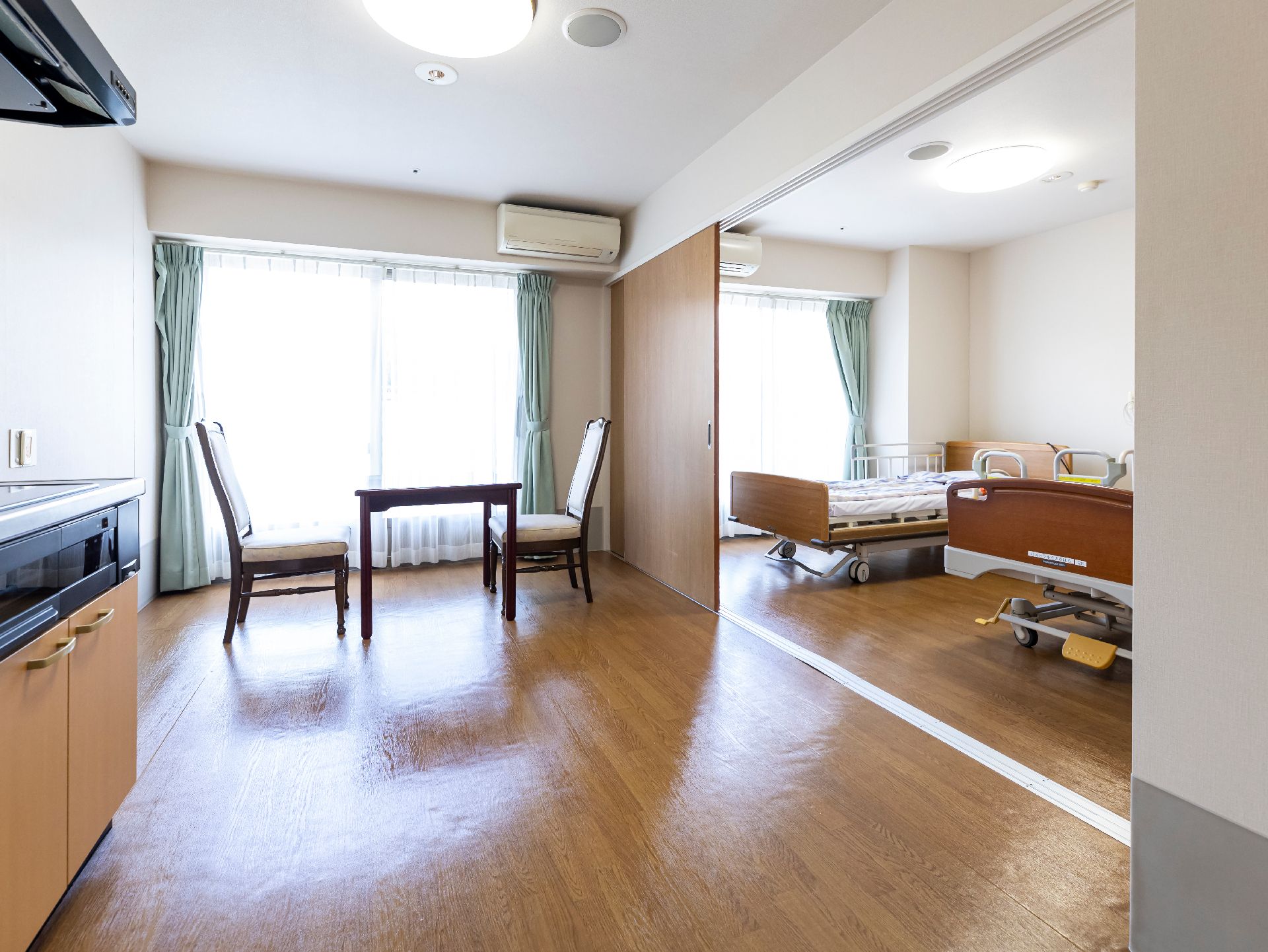 窓から日差しが入り、ベッド、椅子、テーブルなどが置かれている居室
