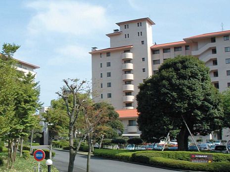 白を基調とした大きなマンションタイプの施設にはオレンジの屋根が付いている。周りには草木が植えられている。