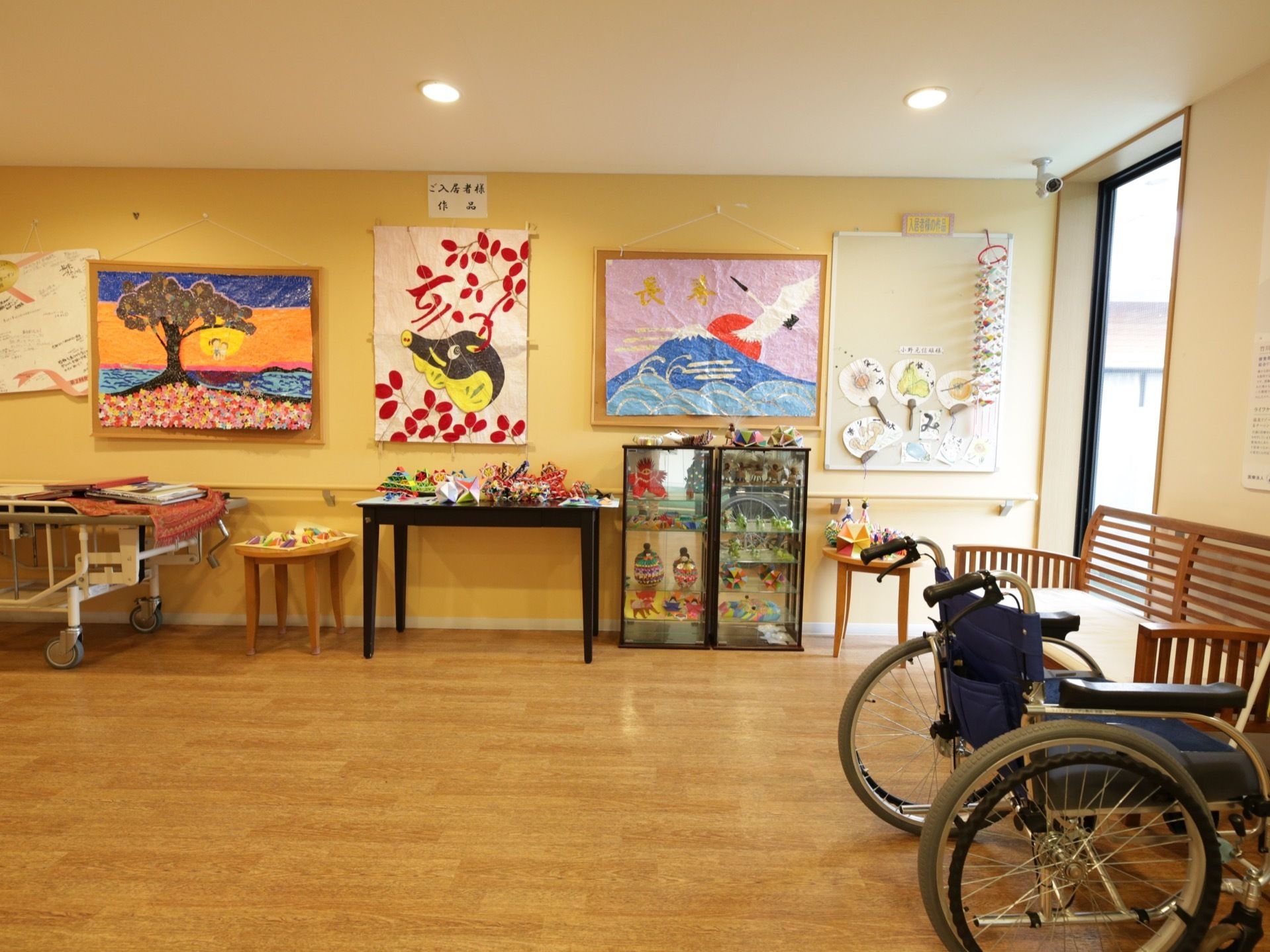 入居者様の作品が数多く展示されている。大きなものは壁に貼り付けられ、小さいものはテーブルの上や飾り棚の中に置かれている。