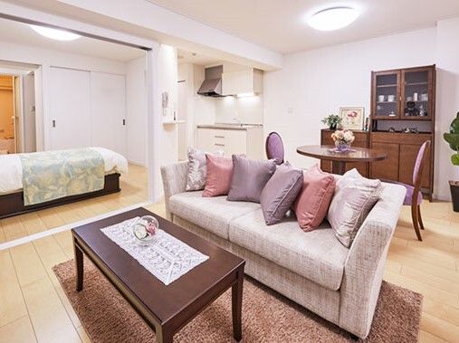 フローリングの居室は寝室とリビングに分かれており、リビングにはキッチンやソファ、テーブルセットが、寝室にはベッドがある。