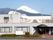 山に囲まれた静かな土地に建つ高齢者向け施設の外観。奥のほうに富士山が見えている写真