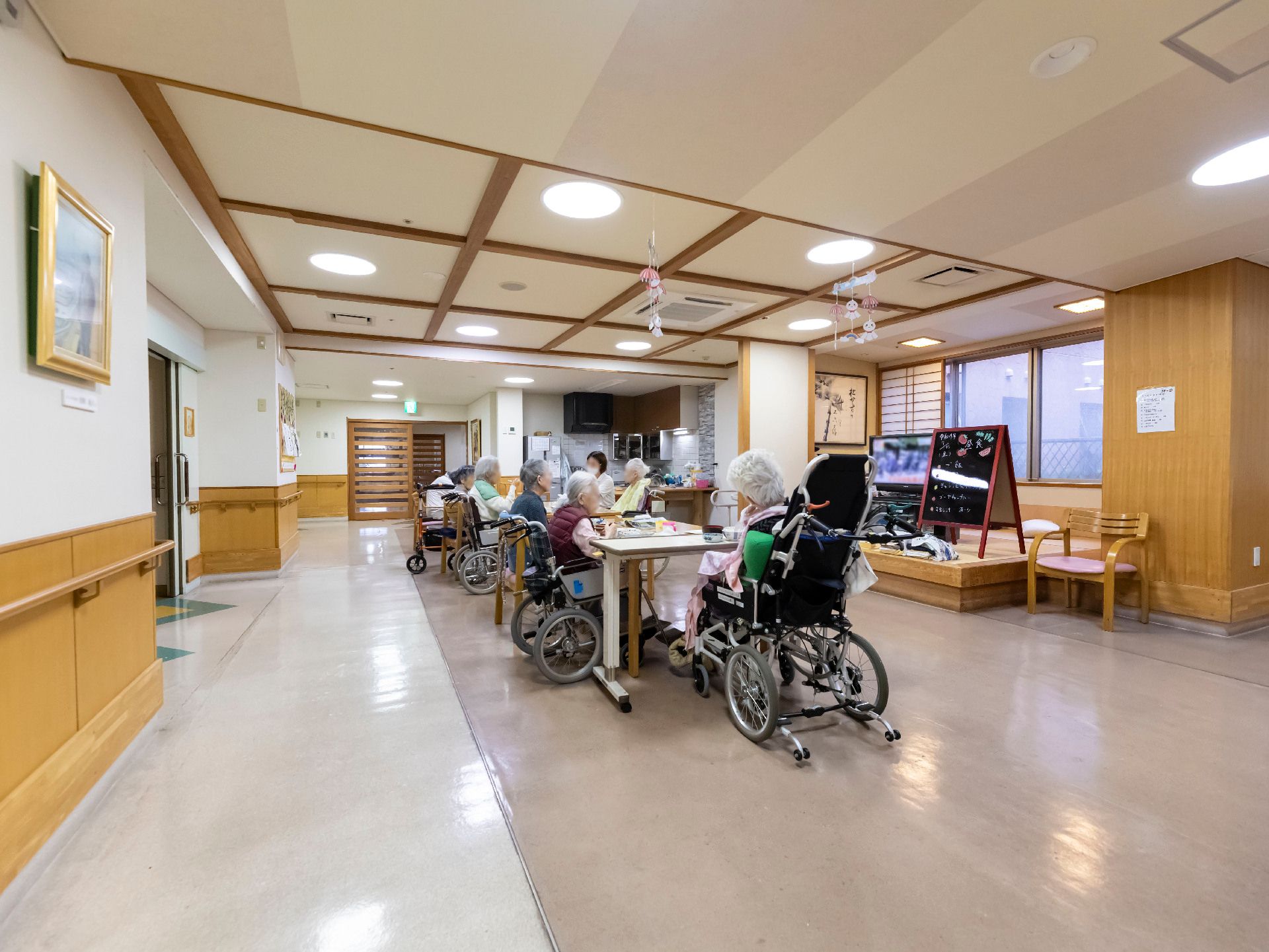 テレビの前の長机の周りに集まる入居者様