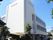 白を基調とした３階建ての建物。玄関先には屋根や手すりが付き、明るい雰囲気。
