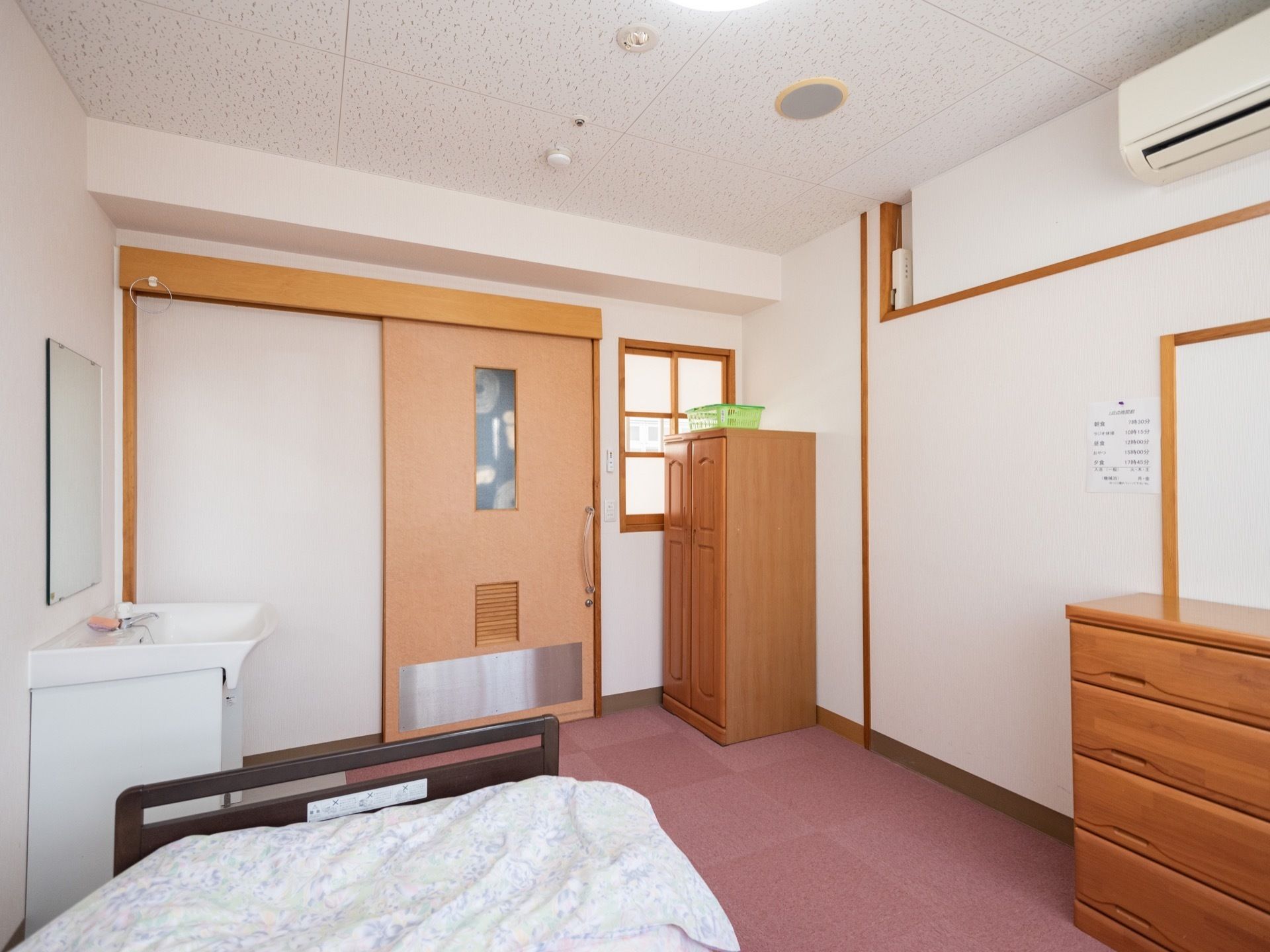 居室の入口は幅の広いスライドドアになっている。床には赤色の絨毯が敷かれていて、天井と壁は白色である。エアコンが設置されている。