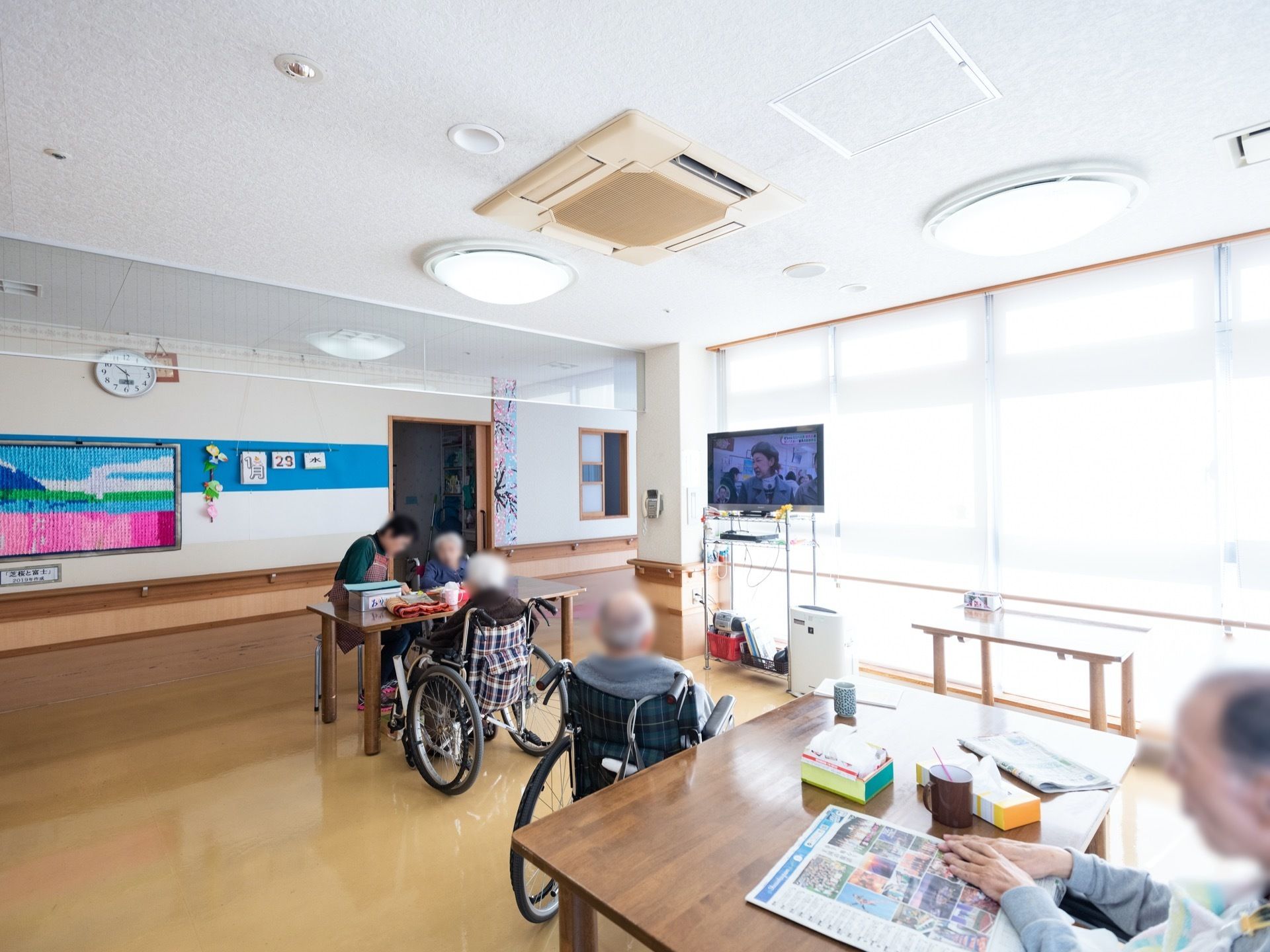 共有スペースには、空気清浄機やテレビ、テーブルなどが置かれている。床はベージュ系でキレイに磨かれている。