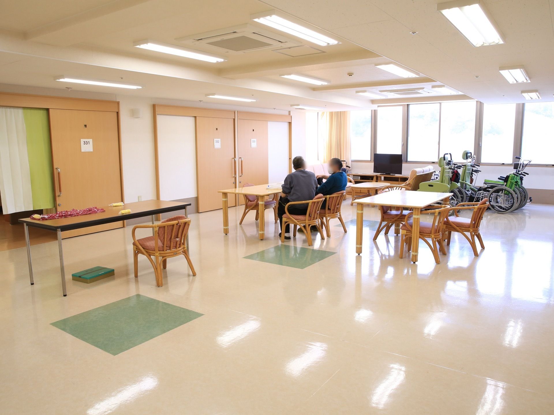 共有スペースが居室を出てすぐ目の前にある。男性の入居者様が２人、並んで椅子に座って、おしゃべりをしている。
