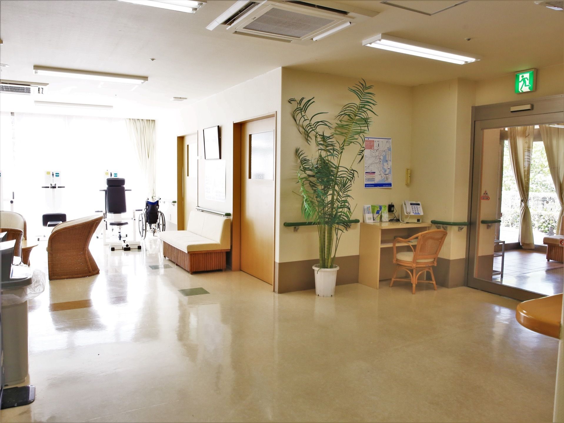 自動ドアが完備され、上部には非常口を示すランプがある。壁に手すりを設置している。背丈のある観葉植物も置かれている。