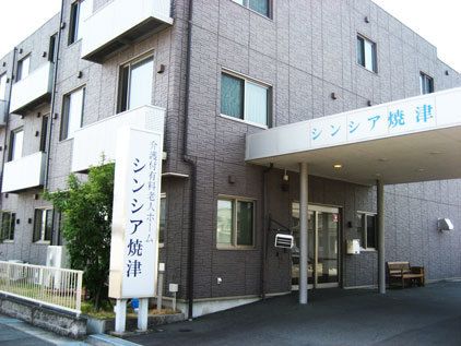 「シンシア焼津」の看板が出ている建物の写真。雨除けが付いているエントランス