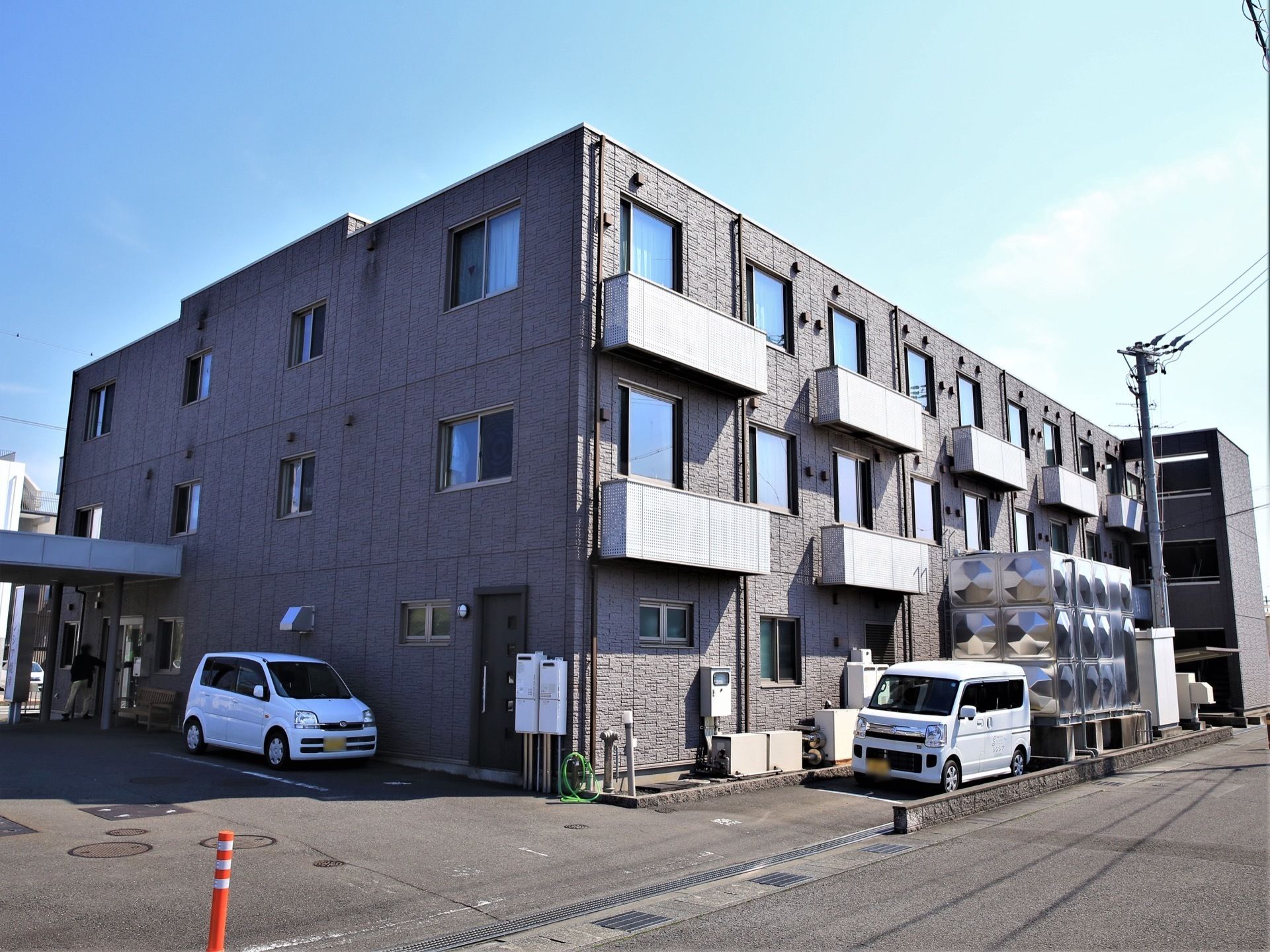 3階建ての近代的な建物が当施設である。落ち着いたシックな外壁が特徴である。敷地内には駐車スペースも設けられている。