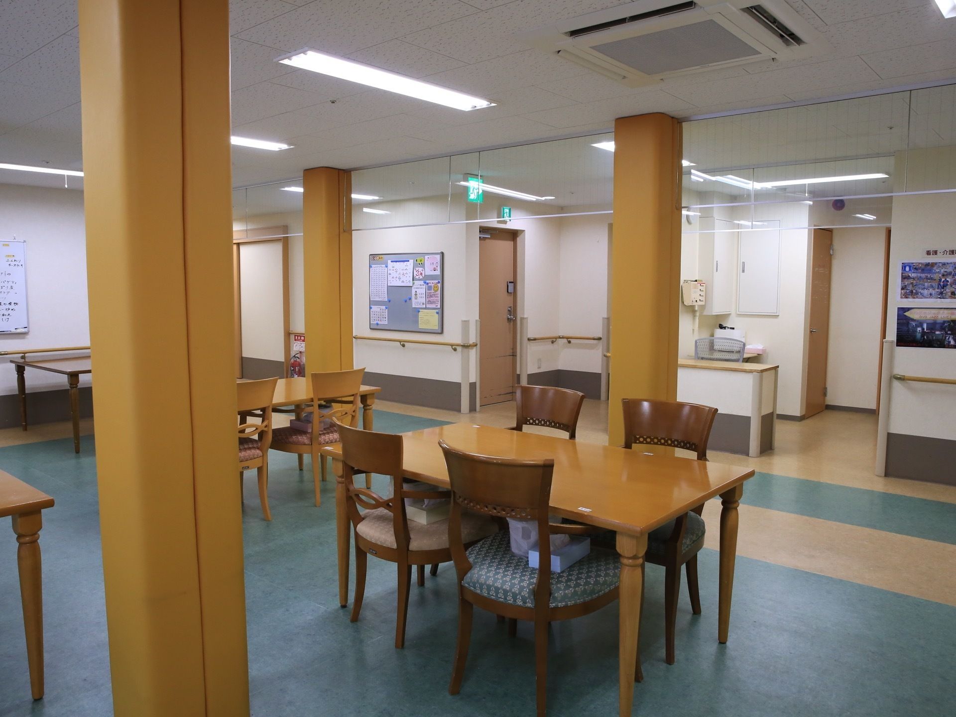 食堂に、テーブルと椅子が多く置かれている。椅子の上に、ティッシュペーパーの箱やくずかごが載っている。