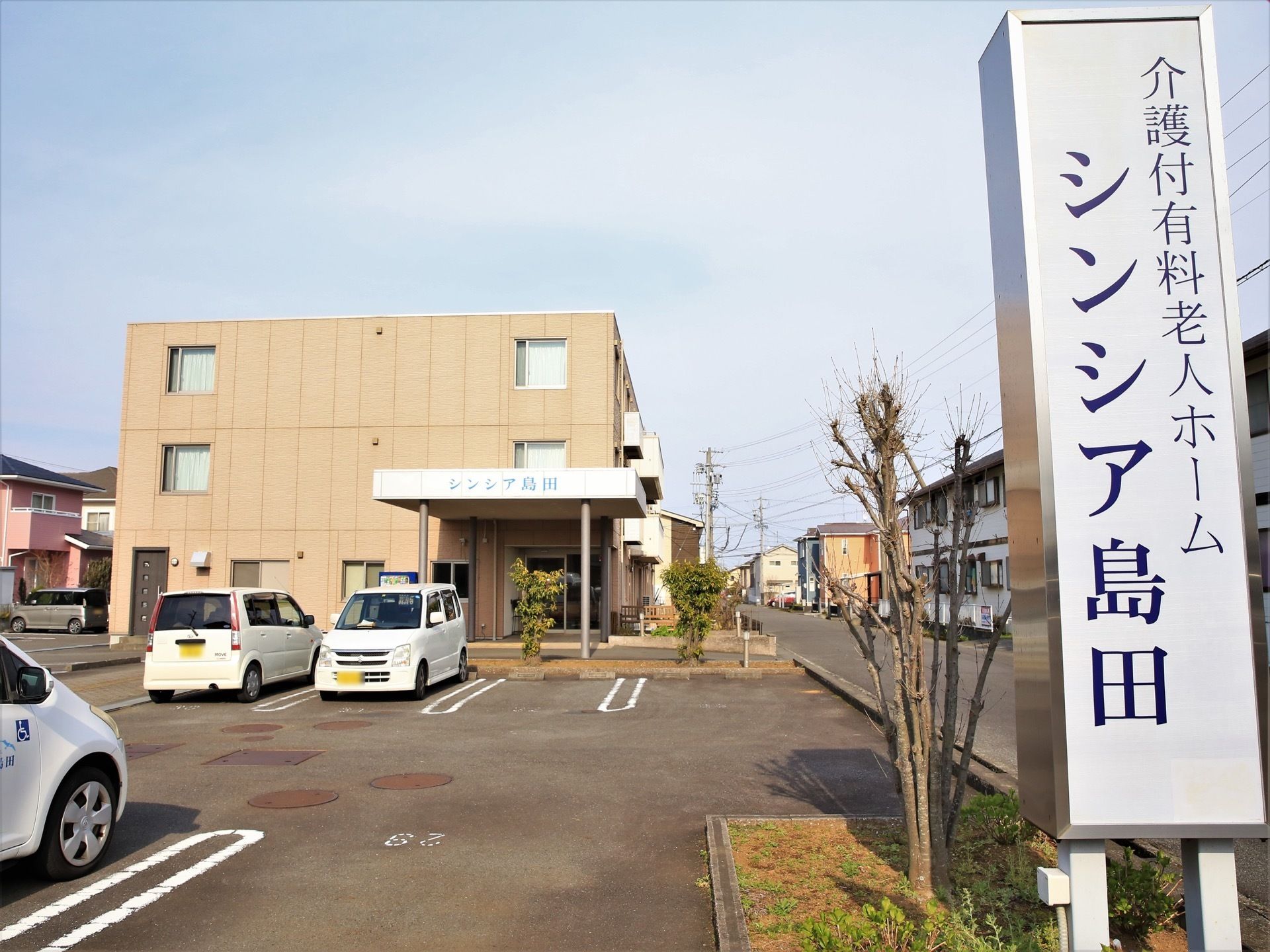 住宅街の一角にある敷地に建っている３階建ての施設である。提供サービスと施設名称を表示した看板が道路沿いに設置されている。