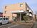 玄関の前方に屋根が張り出していて、施設名称が表示されている。建物の周囲はアスファルトで舗装されており、駐車区画も示されている。