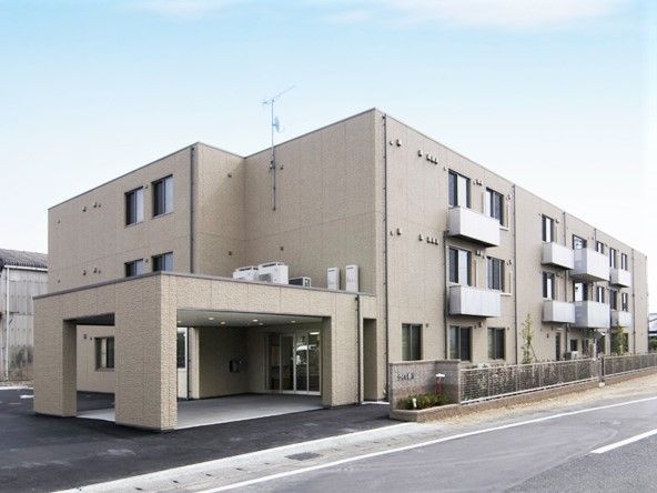 横に長い鉄骨造の建物の外観。エントランスに大きめの雨除けがついた介護付き有料老人ホーム