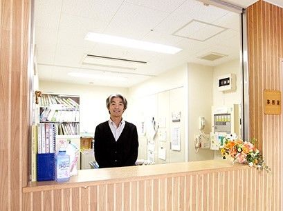 花やアルコール消毒が置かれた受付。男性スタッフが微笑んでいる。