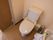 トイレは、温かい便座で温水機能付きとなっている。木目調のスライド式扉が設置され、壁には手すりが取り付けられている。