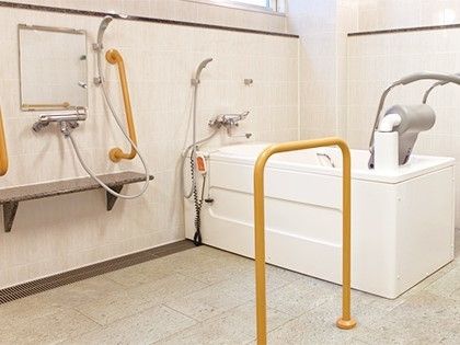 リフトが設置された白い浴槽の横にはシャワーが設置され、その横にはもう一つシャワースペースがある。