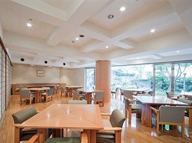 木製のダイニングテーブルが複数並んだ食堂。左には障子風の扉が見え、右側の壁は一面が窓となっていて、庭を見ることができる。