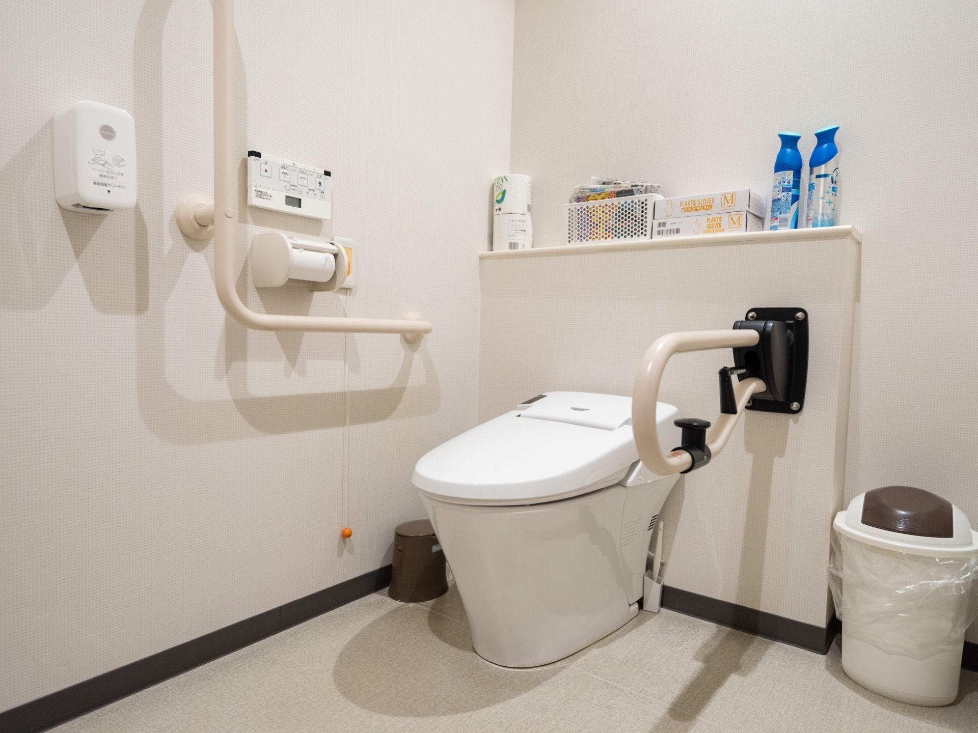 トイレは、白で統一された清潔感のある内装となっている。奥の棚には、トイレットペーパーなどの日用品の予備が置かれている。