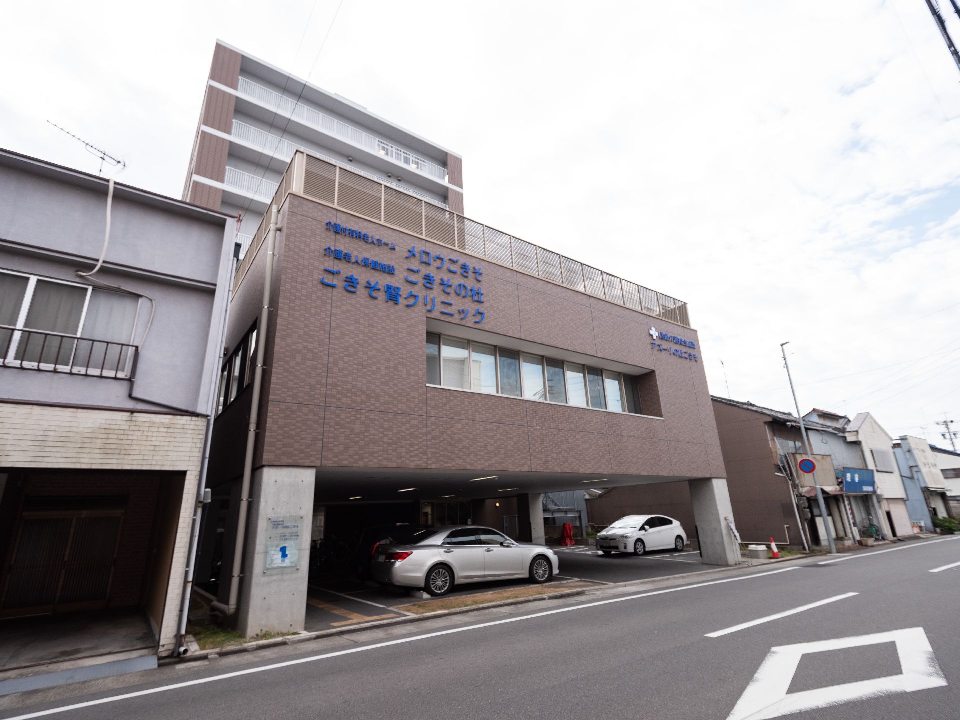 １階が駐車スペースになっており、複数の施設が同居している、レンガ調の外観をもつ建物