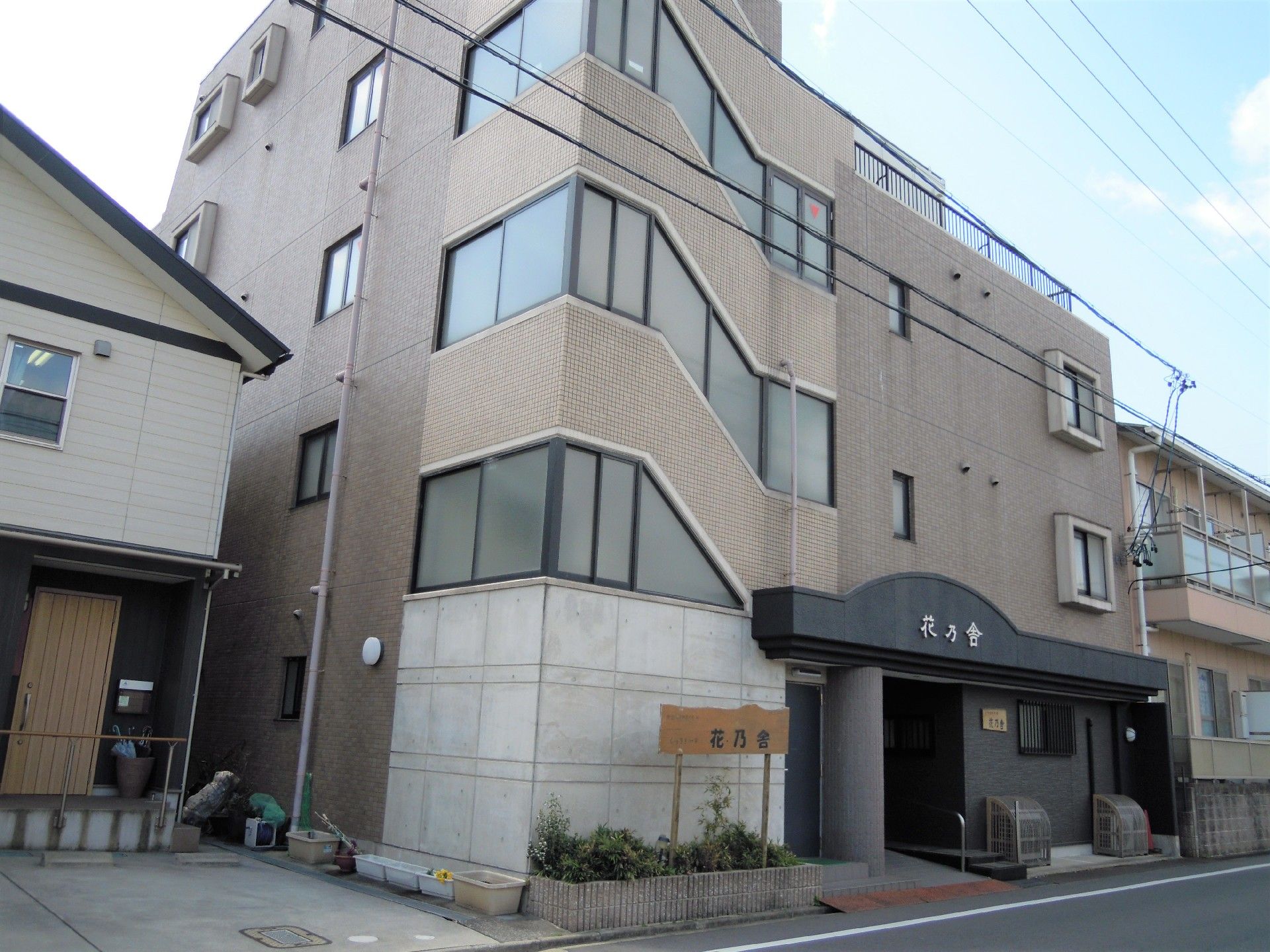 植込みと玄関上に施設名を掲げた、鉄筋コンクリート造の建物