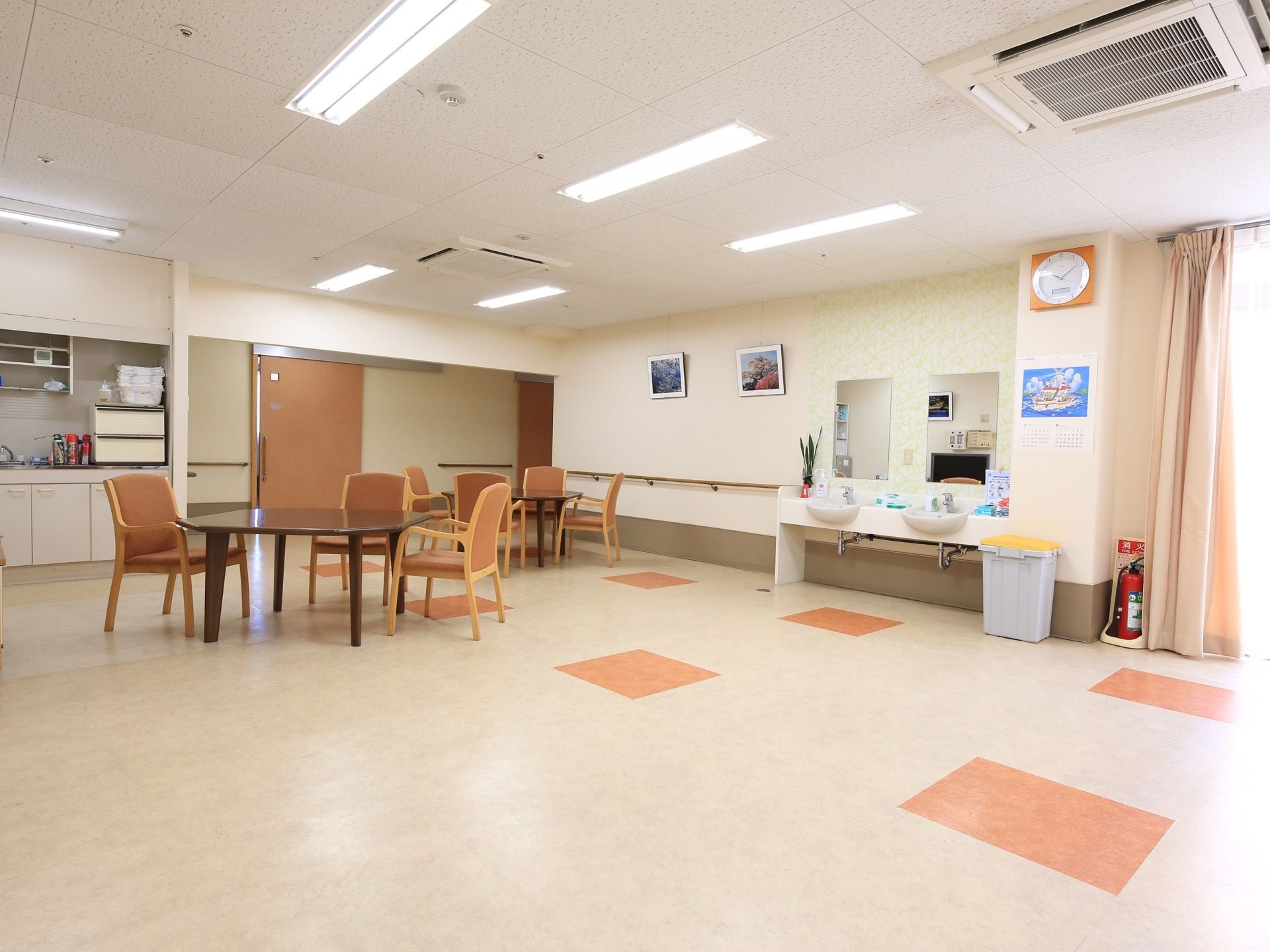 キッチンが完備されている、広い多目的室である。室内には４人掛けのテーブル席が複数設置され、洗面台もある。