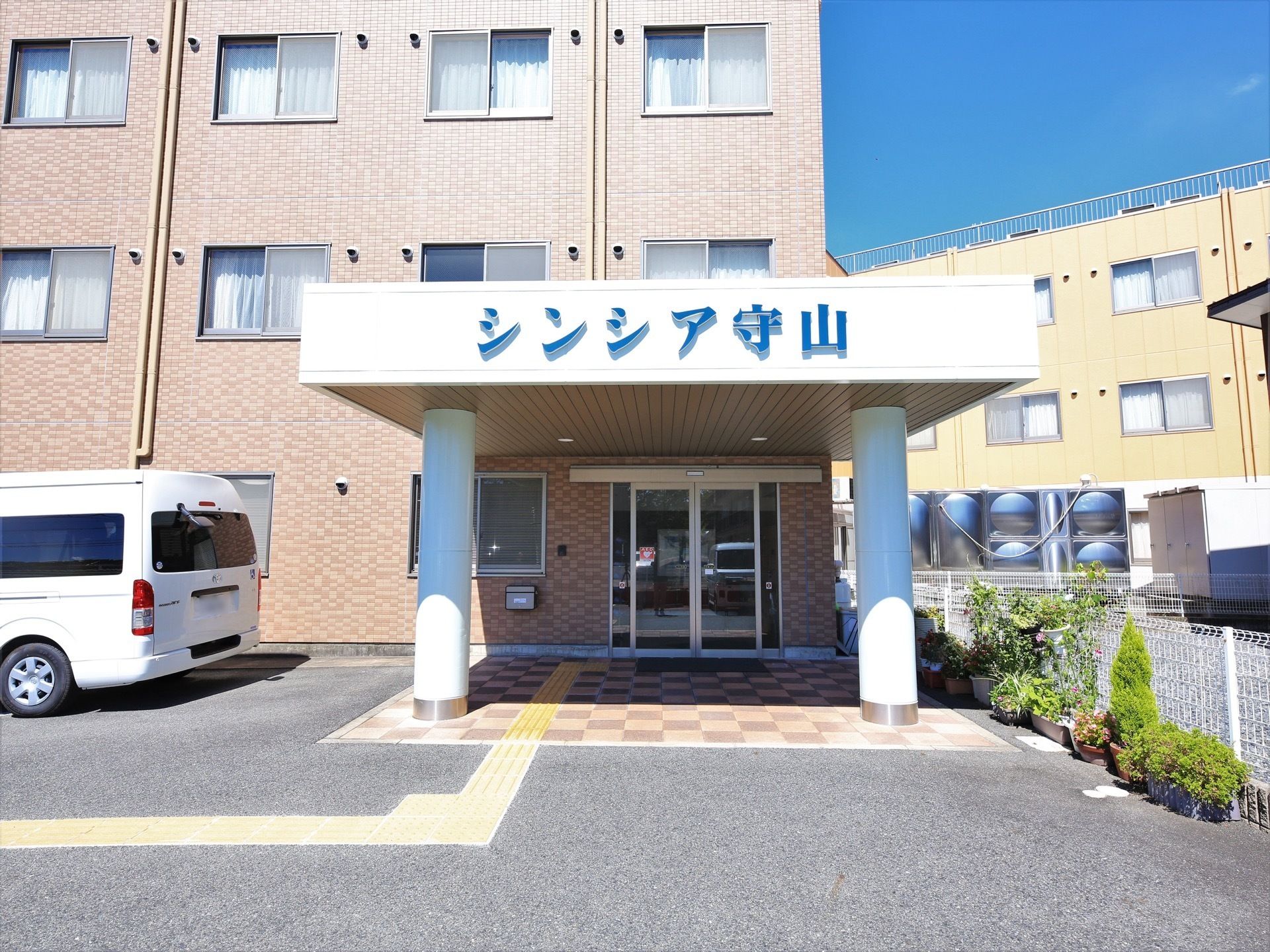 エントランスには屋根が設置され、車寄せとしても使用できる。敷地内の通路は段差が少なく、車椅子や歩行器をご利用の方も安心である。