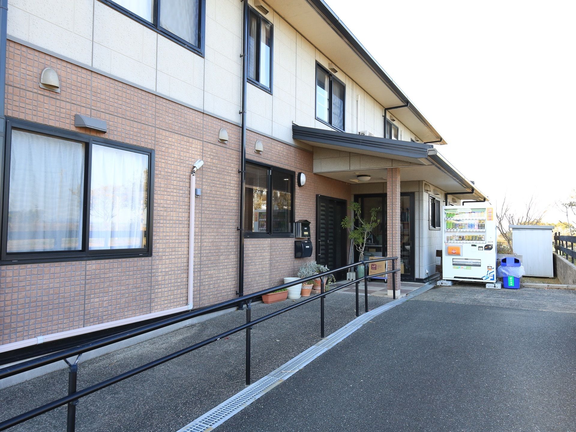 2色のタイル張りが施されたデザインが特徴的な、２階建ての建物である。入口まで手すりが備えられており、掴まって移動することができる。